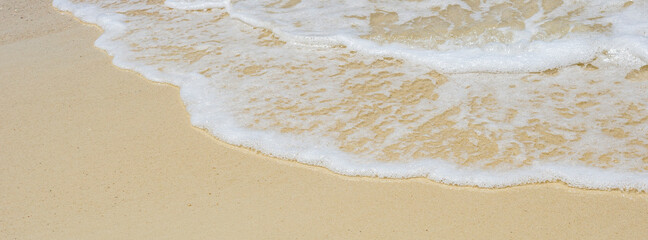 soft wave of the sea on sandy beach texture in bright summer day for banner background