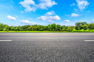 Asphalt road and green forest under blue sky.