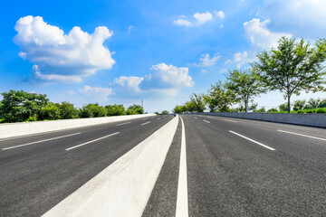 Asphalt road and green forest under blue sky.
