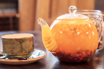 yellow tea in a glass teapot and blue cup on a wooden table