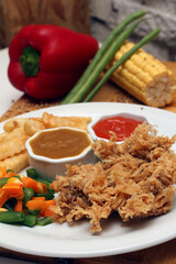 Crispy chicken steak with mushroom sauce, french fries, and fresh vegetables