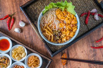A bowl of Liuzhou river snails rice noodle on a wooden table