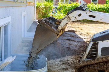 New house under construction window well basement construction bucket standing on gravel stones