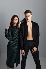 A sexy man in trousers and a jacket stands next to a beautiful woman