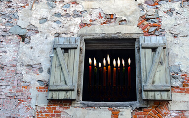 Burning candles in old building with window and shutters
