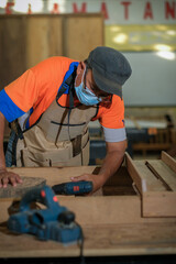 Front view photo of focused professional hardwood worker making slab coffee table portable machine .Woodworking and carpentry production .