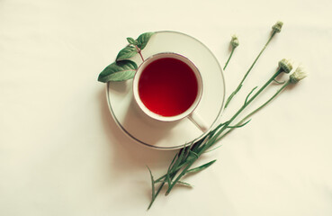 Cup of tea with flowers and green leaves as decoration