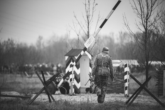 Re-enactor Dressed As World War II German Soldier Holding Zb-30 Light Machine Gun. Soldier Holding Weapon. German Military Ammunition Of A German WW2 Soldier. Photo In Black And White Colors