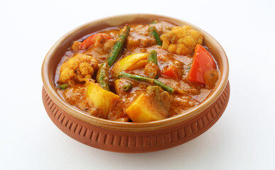MIX VEGETABLE CURRY- indian recipe, mixed veg , Carrots, cauliflower, green peas and beans with traditional masala red hot and spicy served in a ceramic bowl