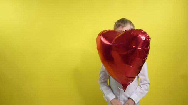 boy holding a big balloon in the shape of heart and amusingly emotionally indulges. Congratulations on Valentine's Day, Happy Women's Day Mothers Day.