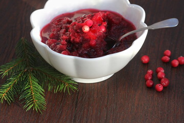 Cranberry jam in bowl with fresh berry on wooden background