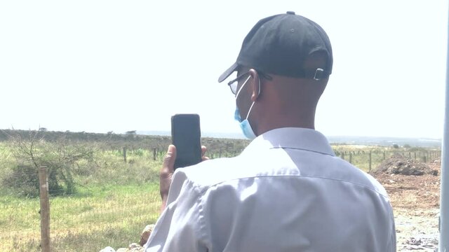 African man take photo with smartphone, looking at savanna scenery