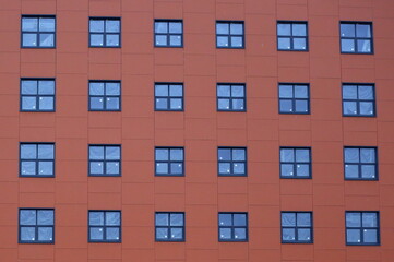 Red facade of a house with different-sized Windows, Kremnchugskaya ulitsa 17, Saint Petersburg, Russia, December 2020