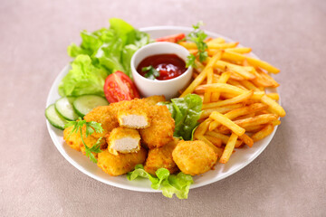 plate with chicken nugget, french fries and vegetable salad