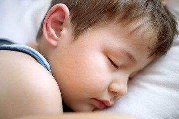 The boy is sleeping on a white pillow. Portrait of a Caucasian child in close-up with closed eyes. Sweet baby dream