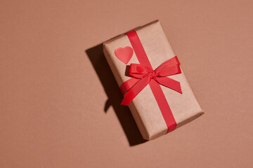 Valentine day composition. Present or gift box wraped in craft paper with heart on pastel background