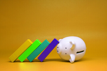 Domino effect with Piggy bank isolated on yellow background with copy space for text message - bankrupt of Fund Investment , no money - yellow concept of Banking and finance concept 