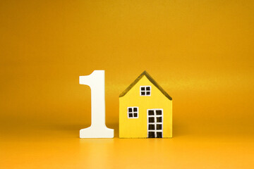 First House , Number 1 ( one ) with wooden home Isolated yellow Background and Copy Space - House property  Business building and finance loan Concept
