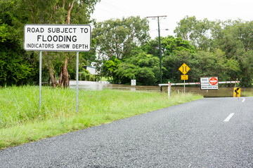 Warning sign road subject to flooding and now closed due to water over bridge.