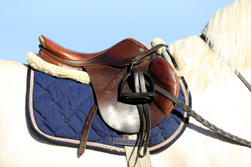 Old leather saddle with stirrups for show jumping race