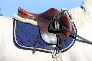 Old leather saddle with stirrups for show jumping race