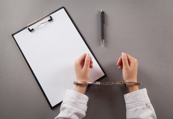Woman fills out documents with handcuffs.