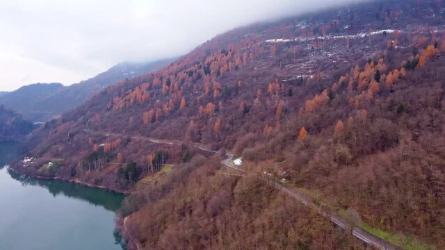Drone  footage Flying above the Levico Lake with red woods on the sides. Dolomiti lake levico terme aerial view 