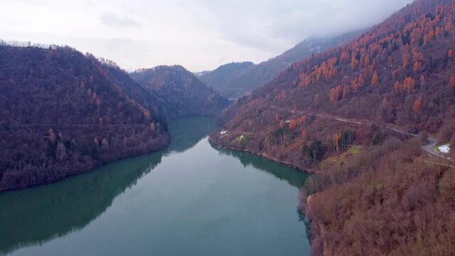 Drone  footage Flying above the Levico Lake with red woods on the sides. Dolomiti lake levico terme aerial view 