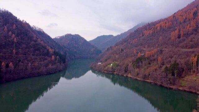 Drone  footage Flying above the Levico Lake with red woods on the sides. Dolomiti lake levico terme aerial view 