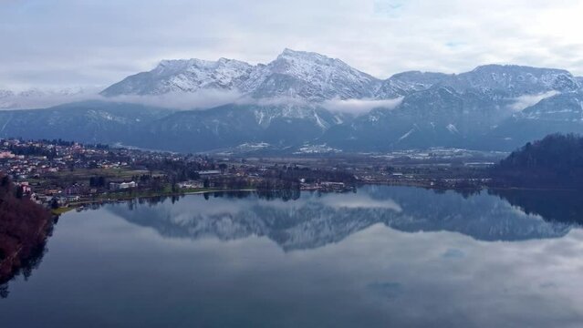 Drone aerial video footage above the Levico lake, facing the mountain Pizzo di Levico, with Forte Spitz Vezzena on the very top. Flying above the water