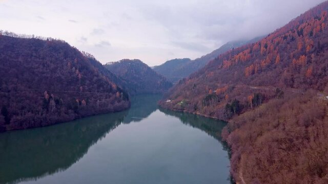 Drone  footage Flying above the Levico Lake with red woods on the sides. Dolomiti lake levico terme aerial view 