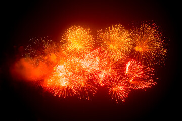 Bright red and yellow fireworks in the black night sky on a festive day