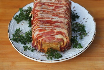 Meatloaf wrapped in bacon with herbs