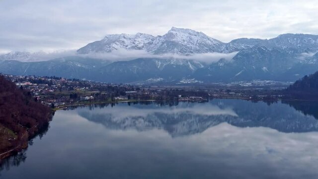 Drone aerial video footage above the Levico lake, facing the mountain Pizzo di Levico, with Forte Spitz Vezzena on the very top. Flying above the water