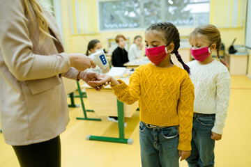 Students wearing medical masks wait in line to take the temperature at school