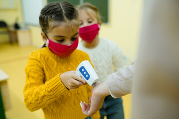 Students wearing medical masks wait in line to take the temperature at school