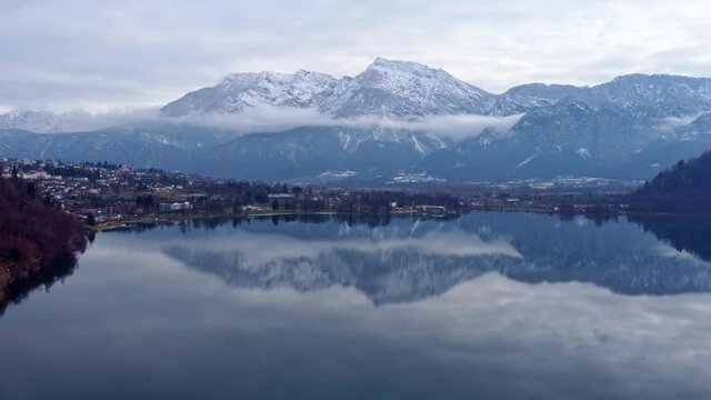 Drone aerial video footage above the Levico lake, facing the mountain Pizzo di Levico, with Forte Spitz Vezzena on the very top. Flying above the water