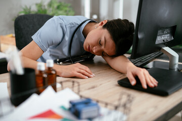 Fototapeta premium Beautiful female doctor working in the clinic. Tired doctor fell asleep in office