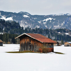 Braune Scheune mit rostigem Dach im Winter im Schnee bei Oberstdorf in Bayern, Deutschland