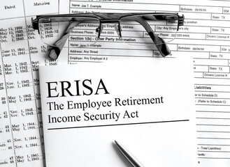 Paper with text ERISA on a financial table with eyeglasses and metal pen