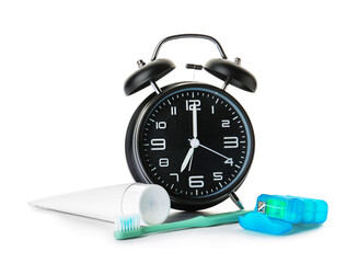Alarm clock, paste and toothbrush on white background