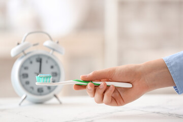 Female hand with toothbrush and paste at home