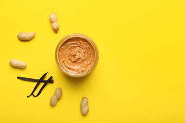 Bowl with tasty peanut butter on color background