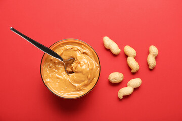 Bowl with tasty peanut butter and spoon on color background