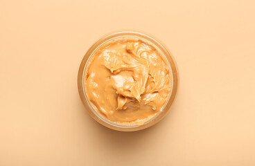 Bowl with tasty peanut butter on color background