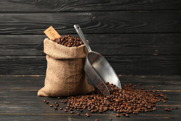 Bag with coffee beans and scoop on dark wooden background