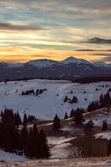 Sunset over snowy peaks in Rila Mountain, Bulgaria. Attractive orange cloudy sky, white slopes, natural landscape panoramic view. Perfect winter conditions for travel, sport recreation and tourism.