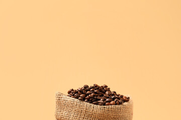 Bag with coffee beans on color background