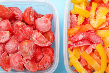 Plastic containers with frozen vegetables on color background, closeup