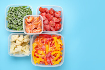 Plastic containers with frozen vegetables on color background